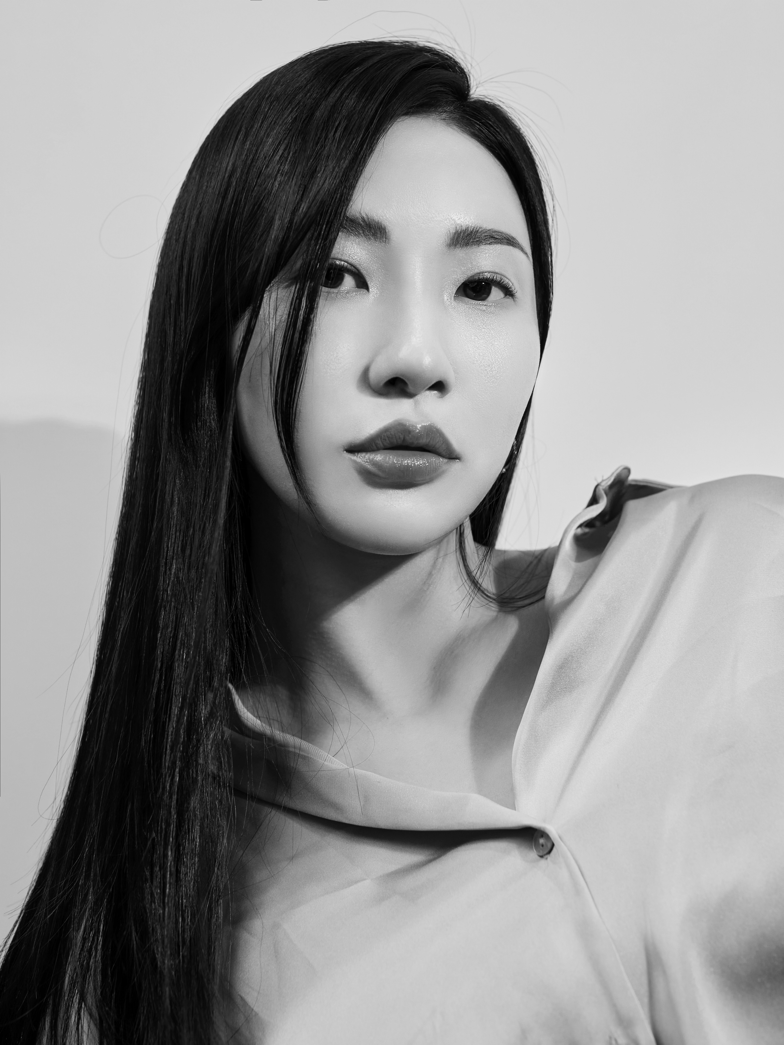 Black and white portrait of a dance instructor posing in front of a dark background.